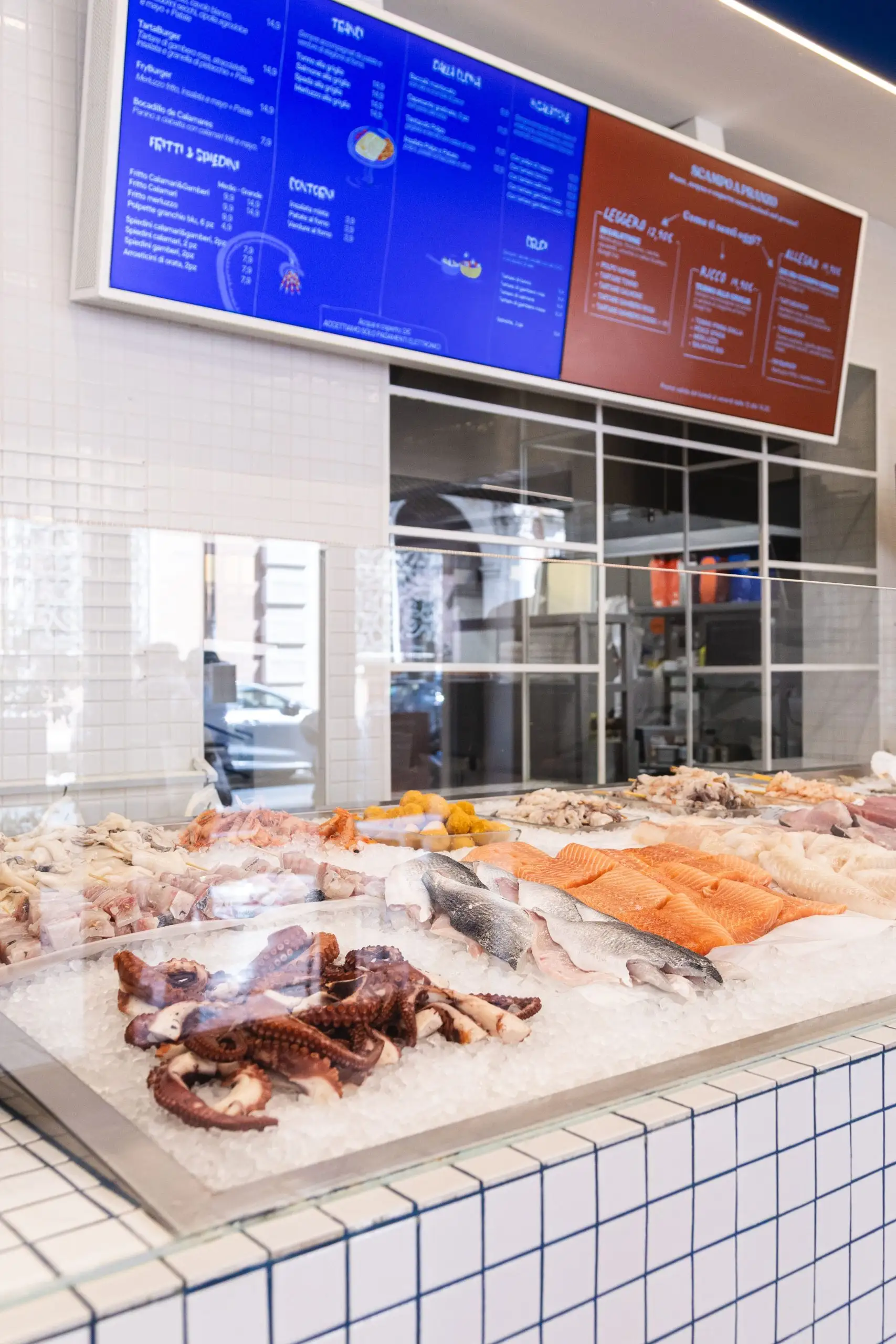 Il banco del pesce con il pescato del giorno sul ghiaccio, sotto i menù luminosi.
